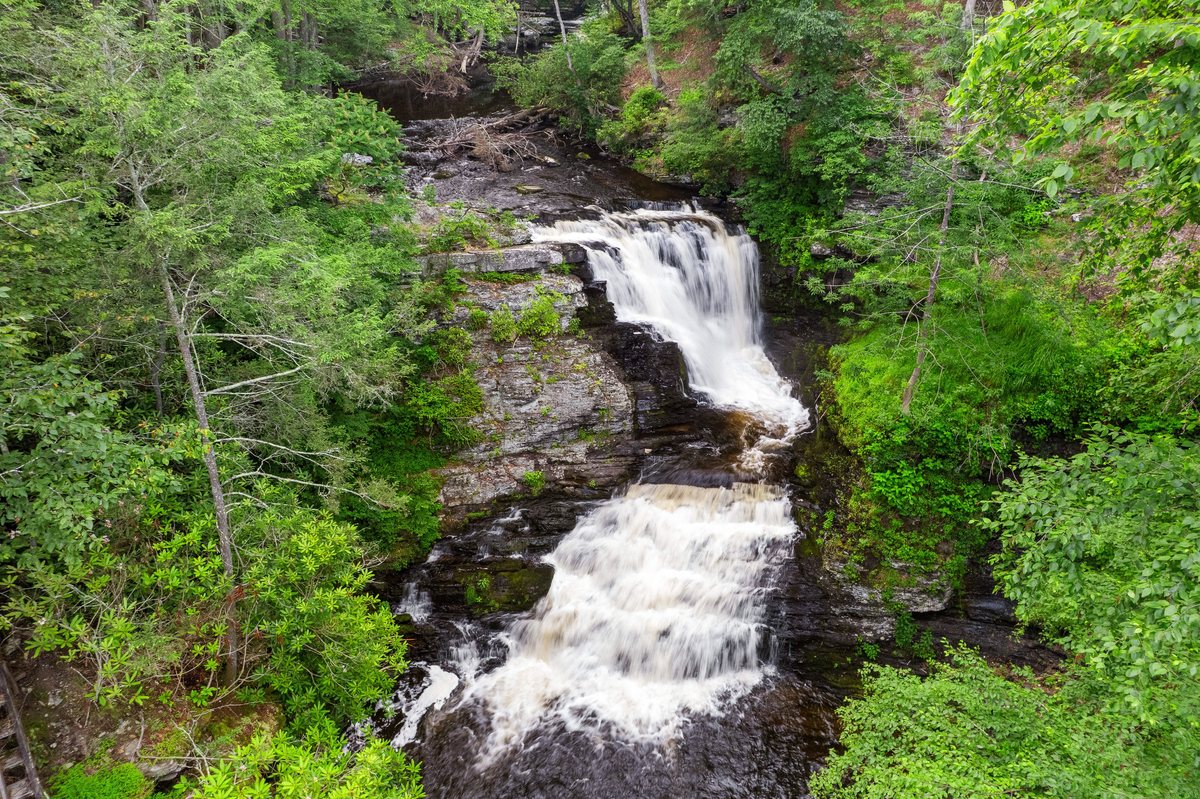 Drone view looking down at the Waterfall Wonder waterfall surrounded by summer forest.