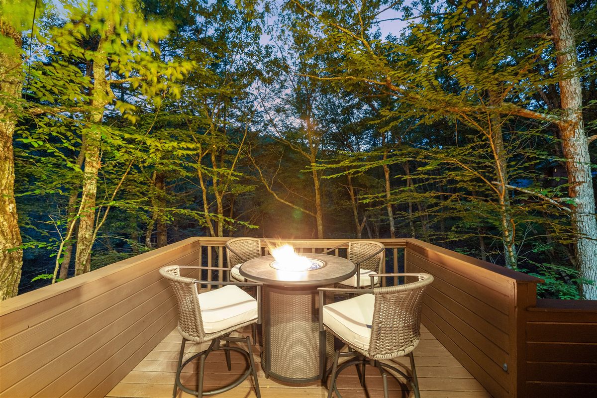 Fire table on a Waterfall Wonder deck at dusk with forest views.