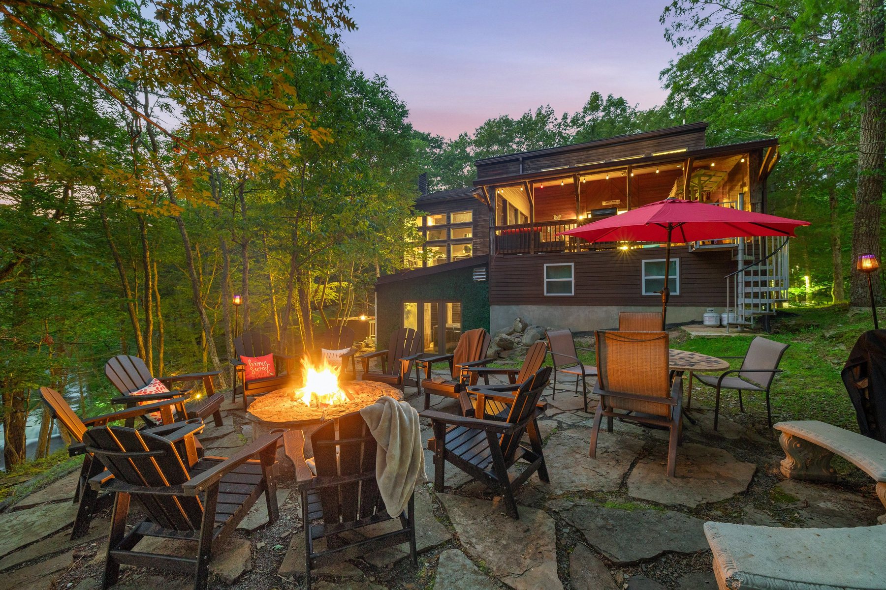 Waterfall Wonder cabin and fire pit glowing at dusk in the forest.
