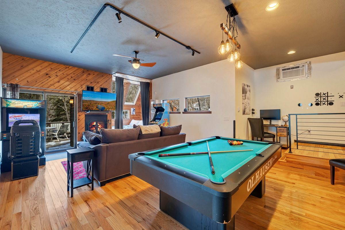 Game room with pool table, lounge seating, and arcade-style entertainment.