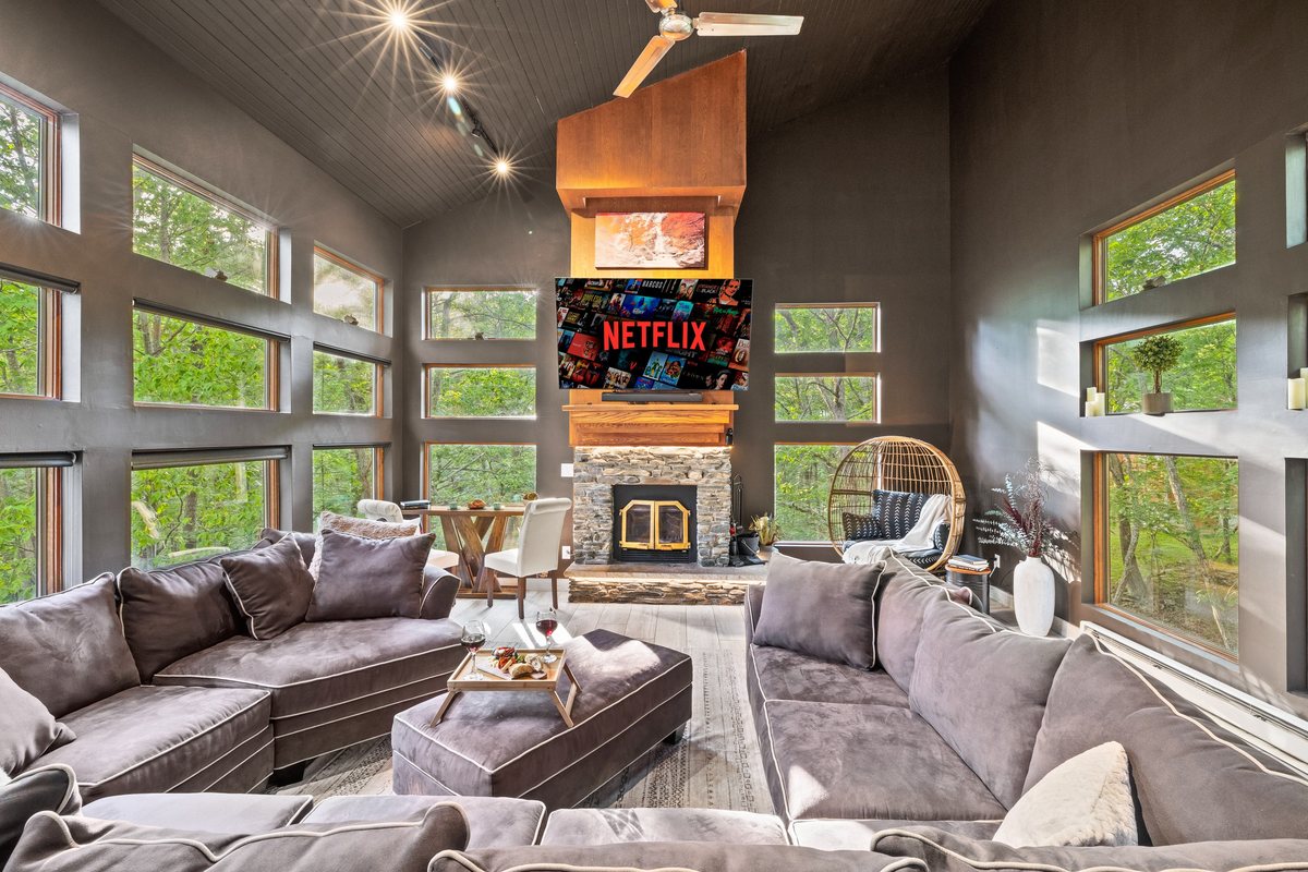 Waterfall Wonder living room with vaulted ceiling, stone fireplace, and forest-facing windows.