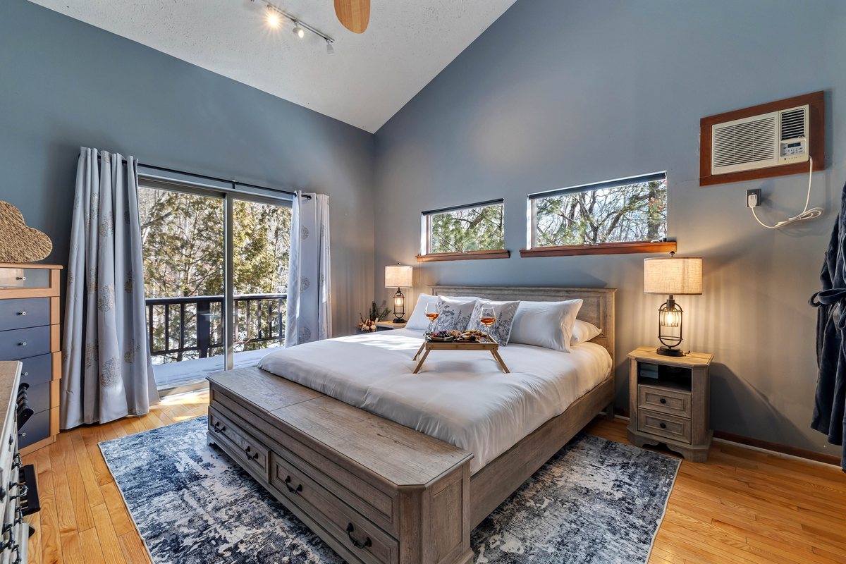 Primary bedroom with warm neutral bedding and forest-house styling.